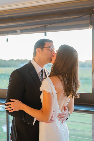 bride and groom kissing in front of sunset