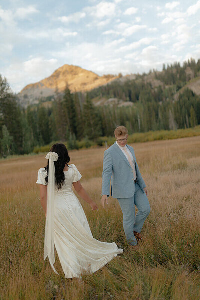 Bridal portraits taken near the Grand Teton mountains. The bride has her back to the camera as the groom is looking back at her.