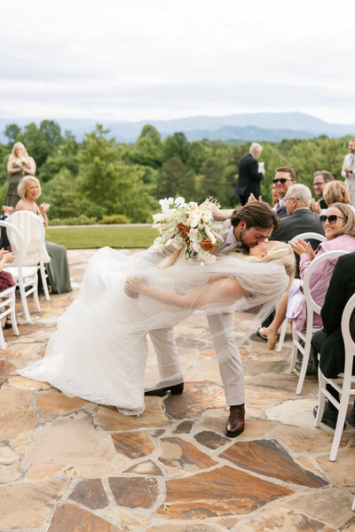 Bride and groom kissing in the ceremony aisle at Tennessee mountain wedding