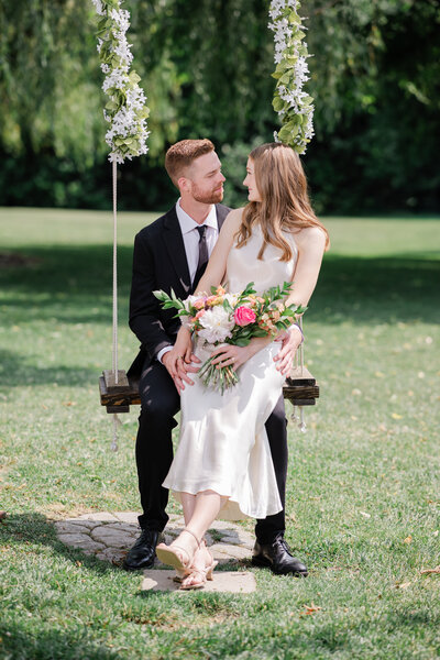 A newlywed couple at their Richmond wedding sit on a swing admiring one anther, taken by Nathan Sottung Photography