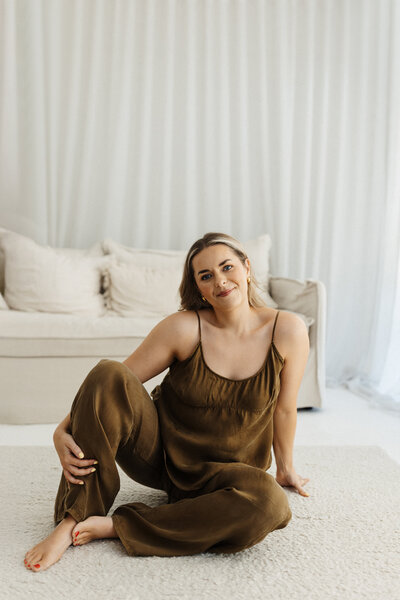 Christchurch photographer Lucy Jane sitting and holding her camera while she is photographed for her branding portraits in her photography studio