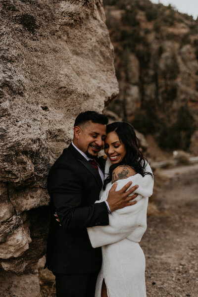 bride and groom standing in front of a lake