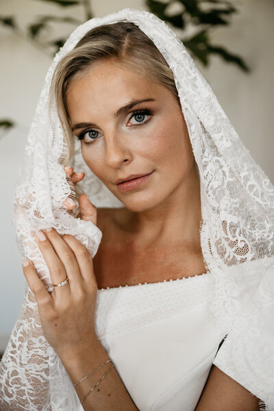 Bruid poseert elegant en kijkt naar de camera.