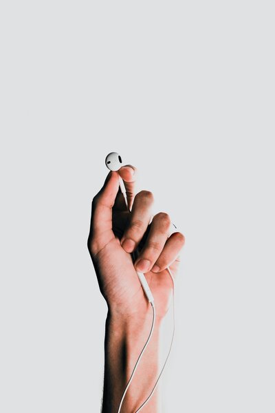 Hand holding ear buds for podcast listening