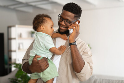 Father on phone holding son and smiling