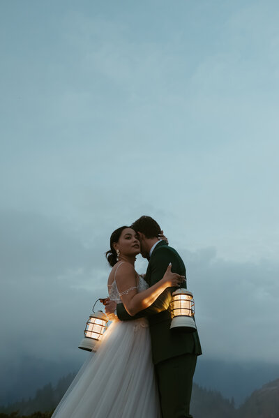 Groom and bride stand top of Mount Baker and play with her dress