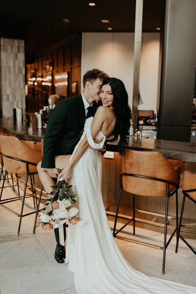 Groom kissing bride posing for camera