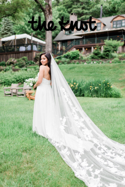 Bride looks over her shoulder and softly smiles into the camera