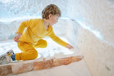 Child playing in salt room at Vitalis wellness studio during halotherapy session for respiratory health