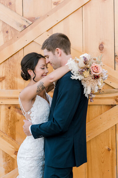 bride and groom embrace in front of barn door