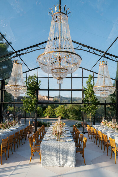 Wedding reception in a white tent with the ceiling covered in white and pink flowers and greenery