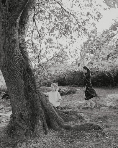 Mother and her son walking barefoot by a big tree in Tähtitorninvuori in Helsinki