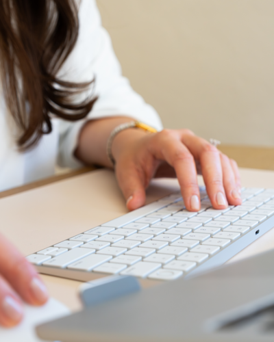 A close-up shot of hands typing on a clean white computer keyboard, symbolizing efficient email marketing and digital communication, associated with the Flodesk platform.