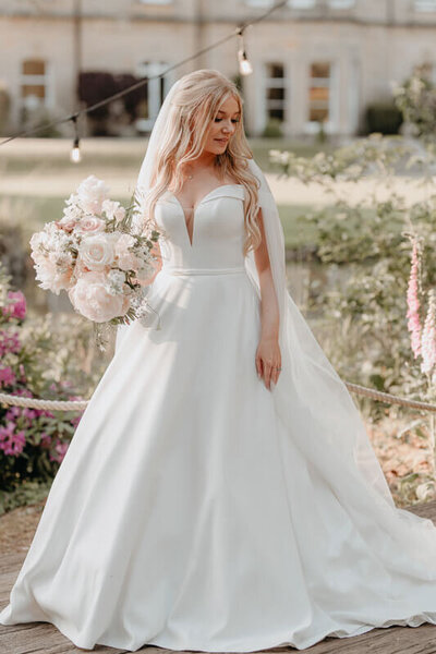 Dreamy bride in wedding dress holding delicate light bouquet