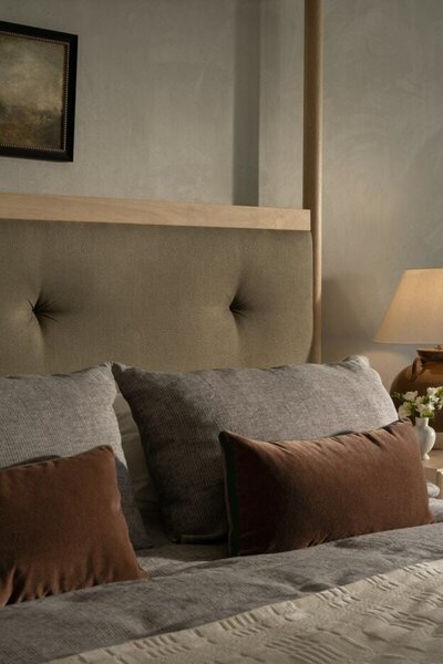 A cozy bedroom featuring a neatly made bed with pillows and a stylish lamp beside it, creating a warm atmosphere.