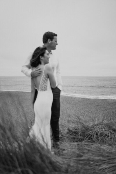 black and white image bride and groom embracing on beach