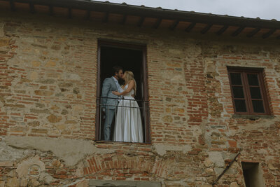 A sophisticated wedding in Italy, where the bride and groom embrace in a passionate kiss inside a historic venue, embodying luxury and timeless love.