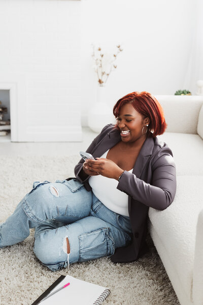 A solo portrait of woman in a blazer answering messages on her phone.