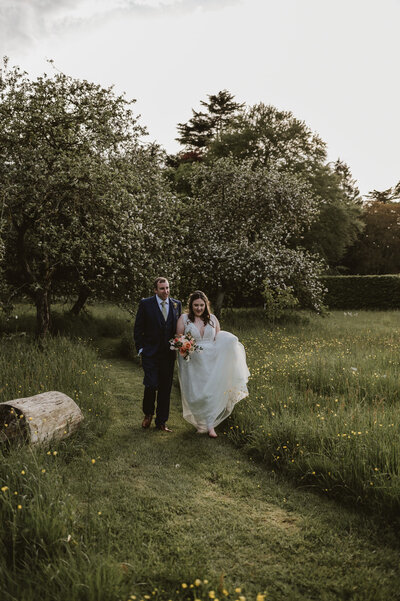 Bride and groom walking through a meadow of flowers