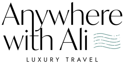 Text logo displaying "Anywhere with Ali" in a modern font, with "Luxury Travel" beneath. Three wavy lines are to the right of the main text, resembling stylized waves. The design is in white.