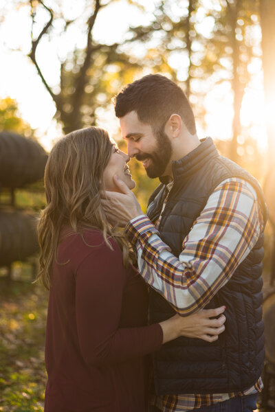 Happy couple embraces and kisses one another during their engagement session at a vineyard. Photographed by Aaron Aldhizer