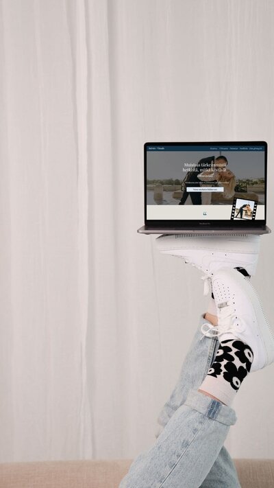 Studiomaiju pitelee läppäriä jalkojen päällä ylhäällä