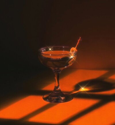 A photo of a cocktail drink in orange lighting being sparkly 