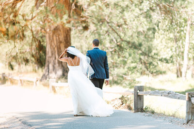 Bride and groom walking away while the wind is blowing her veil