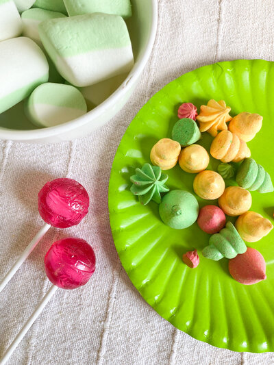 Neon green yellow and pink meringue rosettes on a  wire tray
