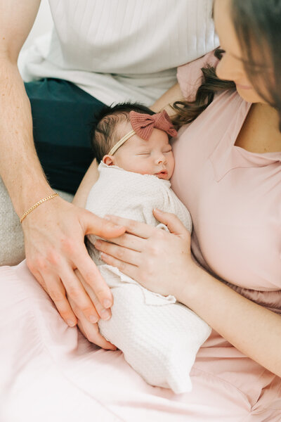 An older brother and sister smile and kiss their new baby brother.