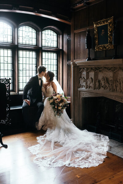 Bride and groom share a kiss by the fireplace at the Hermitage Museum in Norfolk, Virginia 