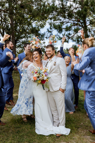 Bride and groom walking down the aisle after saying their "i do's" in a forest with a blue wedding