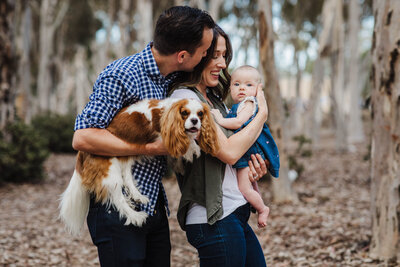 Parents holding daughter and puppy during a photoshoot