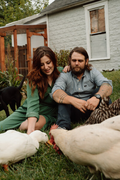 Backyard Kansas City engagement photos with couple feeding their chickens and duck.
