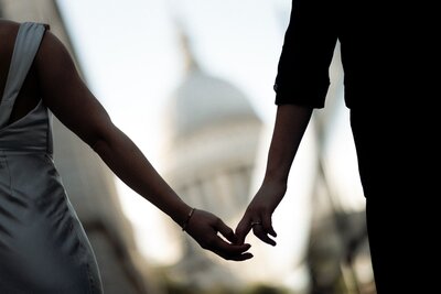 Bride and groom holding hands in front of St Paul's cathedral for wedding photography