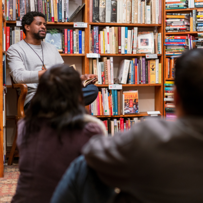 African-American man reading to a group of adults in what looks like a book store