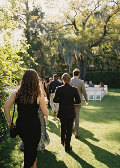 A bride and groom in a cream suit stand at the altar of their boardwalk wedding under palm trees