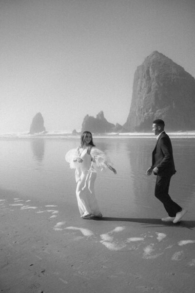 Elopement Couple running along the beach on the Oregon Coast laughing and enjoying their elopement