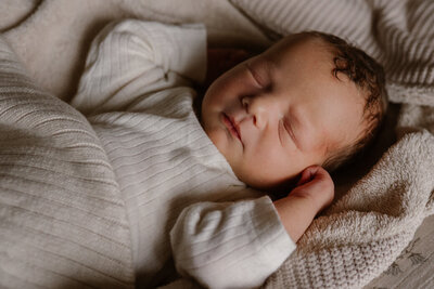 Newborn baby ligt in doeken op het grote bed