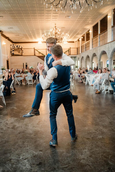 Two grooms dancing in front of their guest