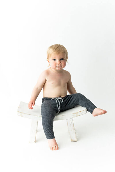 Studio milestone session with a baby boy sitting on a stool.