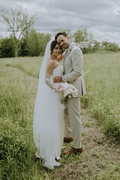 Bride and groom, holding each other in a field