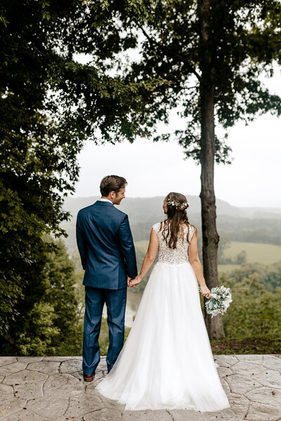 couple holding hands in front of mountains