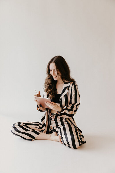 A Content creator writing in her journal, comfy sitting on the floor. 