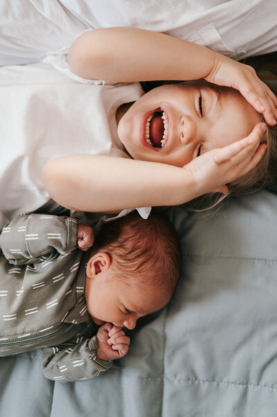 Brother and sister laughing during in-home newborn session