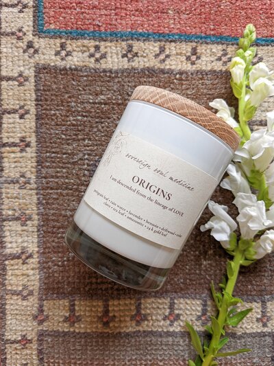 Origins candle on morrocan rug with white flower