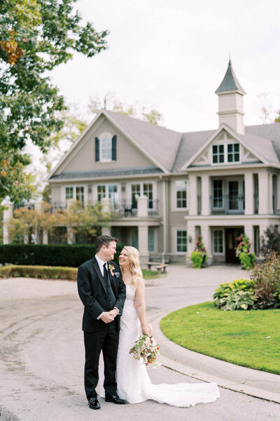 Bride and groom sharing a joyful moment outside Oakville Golf Club in Ontario, captured by Toronto wedding photographer Alexandra Nadtochiy
