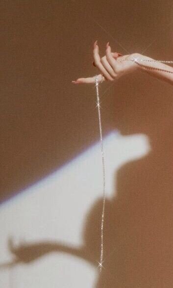 Image showcasing a hand holding a delicate, sparkling chain, representing the subtle enhancements and refined aesthetic promoted by The Complexion Club, a skincare club with an aesthetic-forward website.
