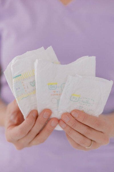 Hands holding multiple newborn diapers