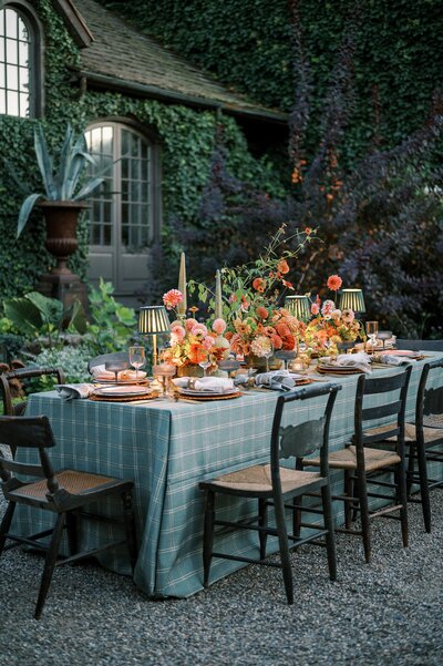 Charming outdoor wedding reception setup in a garden, featuring a rustic wooden table with elegant floral centerpieces and candlelit ambiance.